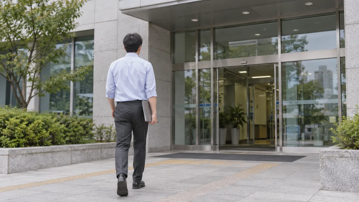 서류철을 들고 공공기관 입구로 향하는 사람의 뒷모습